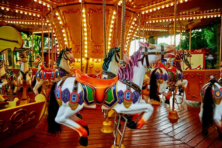 Elegant horse carousel spinning in an amusement park on a sunny day.